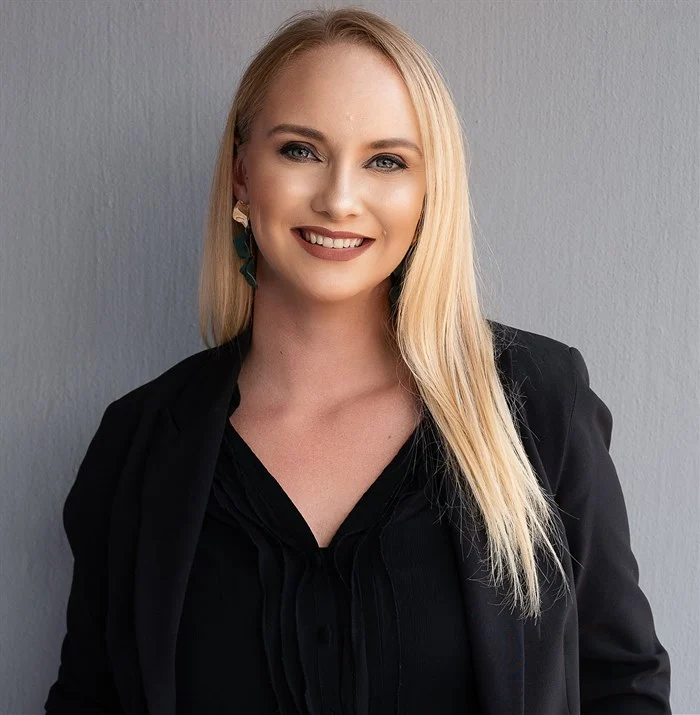 Professional portrait of woman with blonde hair in black blazer.