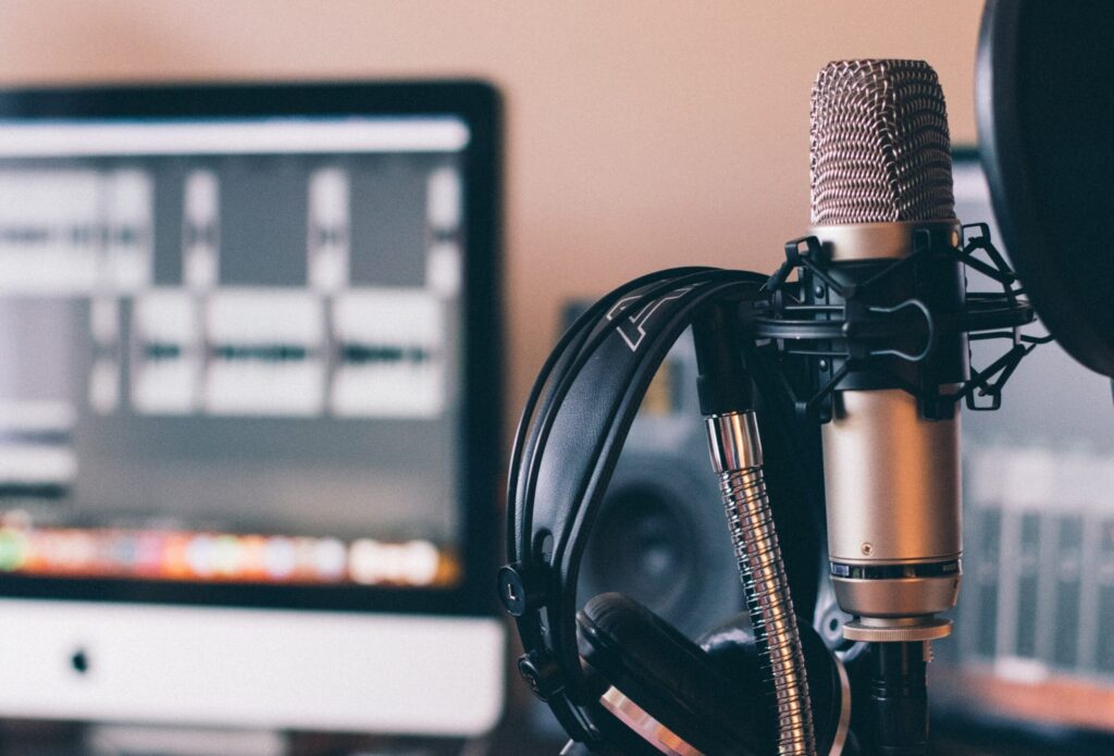 Microphone and headphones positioned beside a computer monitor.