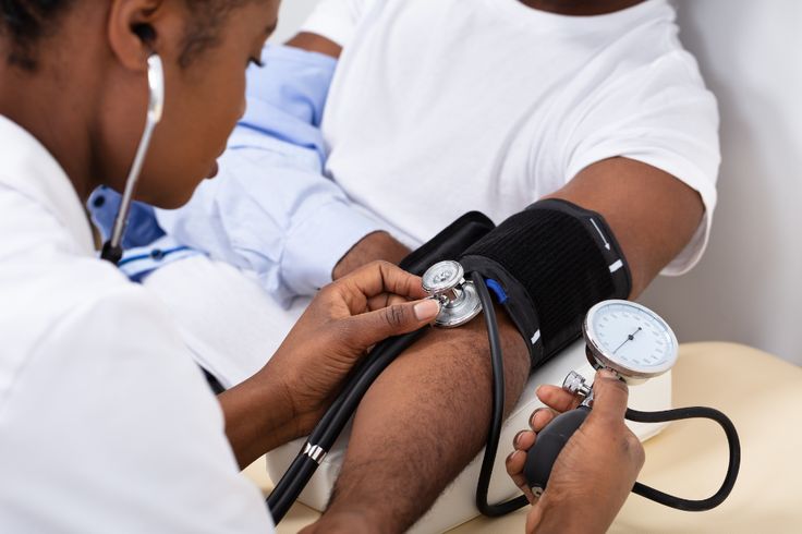Healthcare professional measuring patient's blood pressure with cuff and stethoscope
