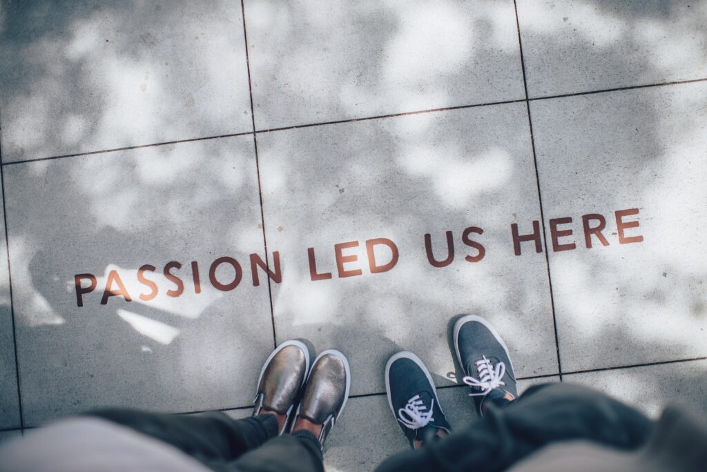 Two individuals stood before text on the ground that reads "passion led us here."